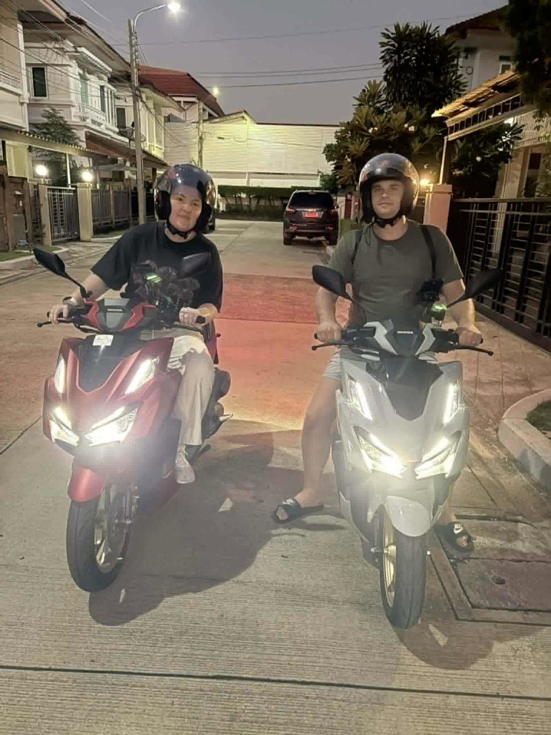 Malene og Ole på hver sin scooter utenfor huset vårt